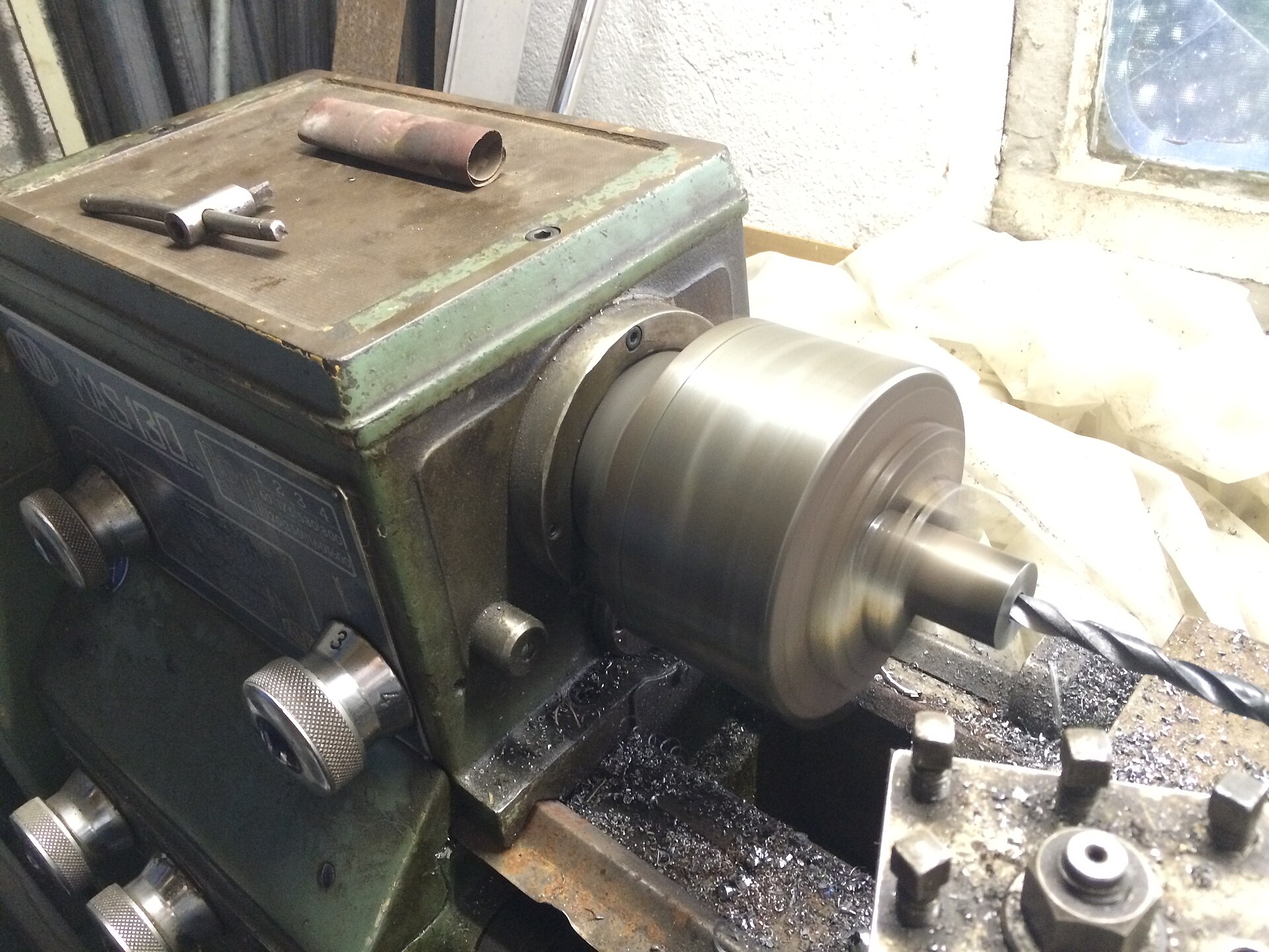 A wood lathe mid-cut with shavings lifting off the spinning blank