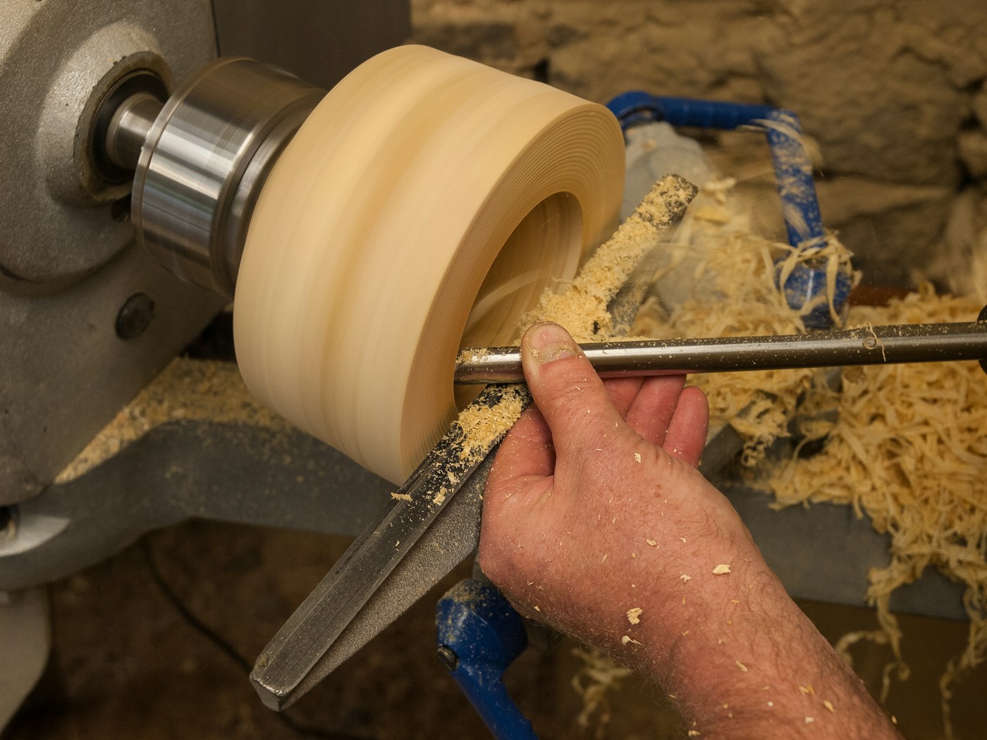 A four-jaw chuck holding a bowl blank on the lathe spindle, with the bowl's outside already shaped