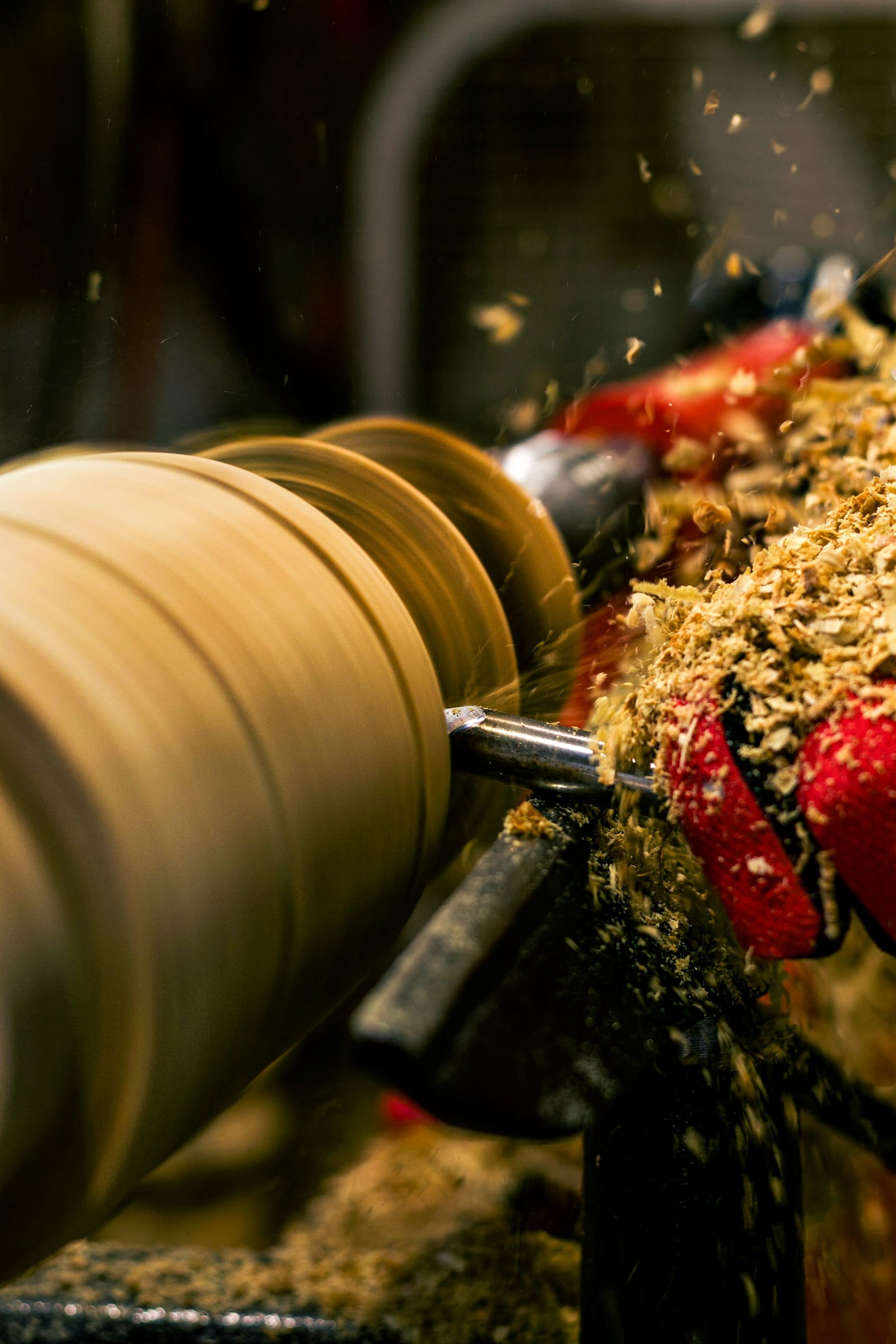A woodturner at the lathe with shavings coming off the workpiece