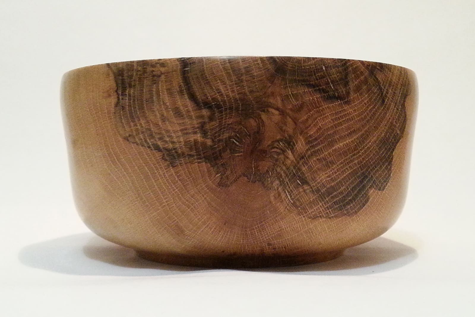 A wide turned wooden bowl with bold dark spalting lines branching through pale oak grain